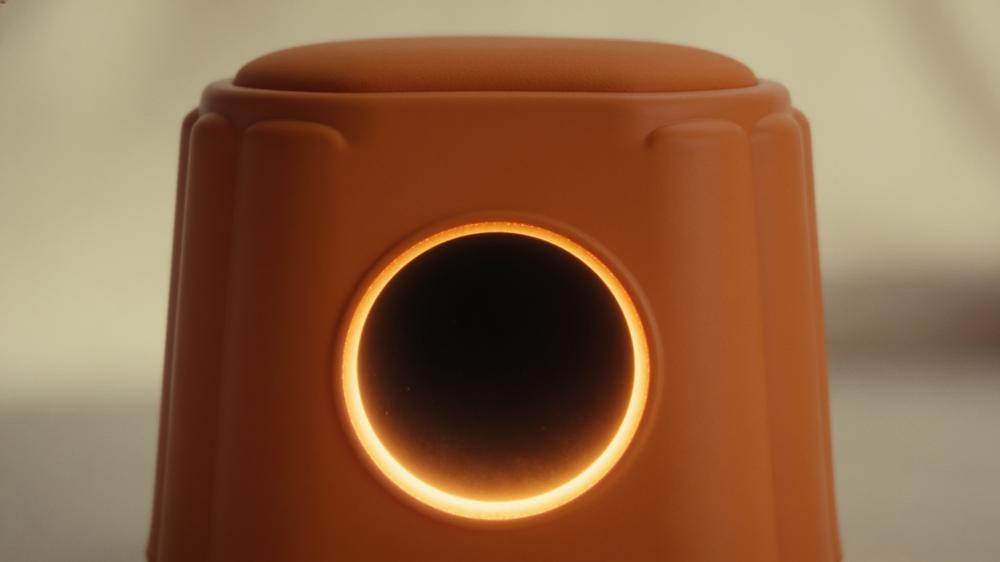 The round door of the orange stool lit from inside like an eclipse